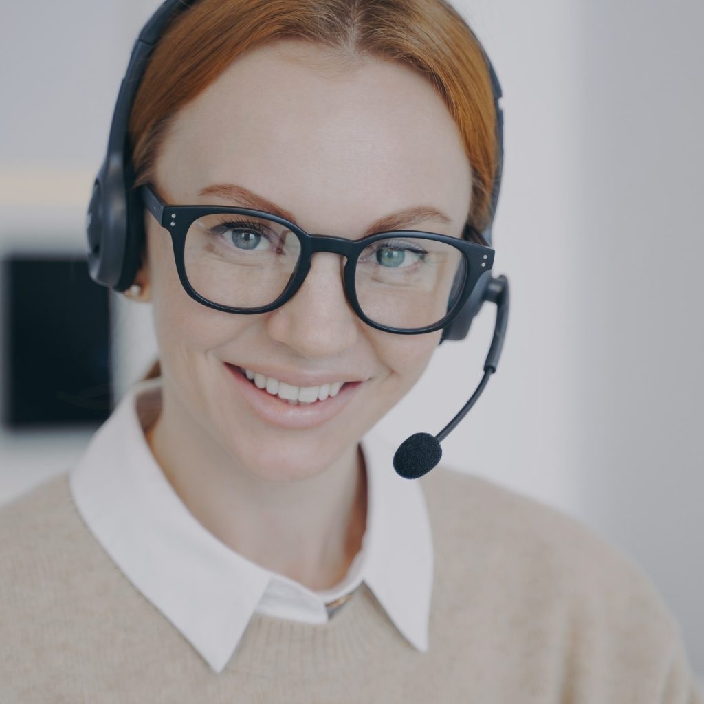 Online consultant of call center. Young woman in earphones provides information by telephone.